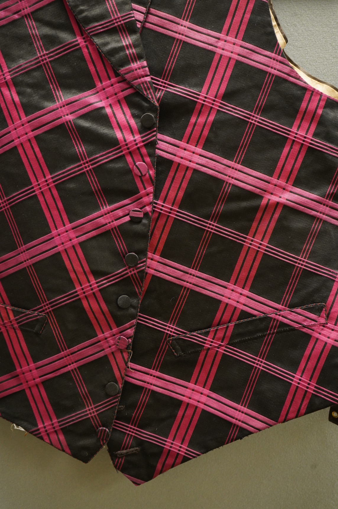 A 19th century gentleman's pink and black silk check waistcoat, with collar and two pockets. Front under arm chest 50cm. Condition - lining stained may need professional cleaning.